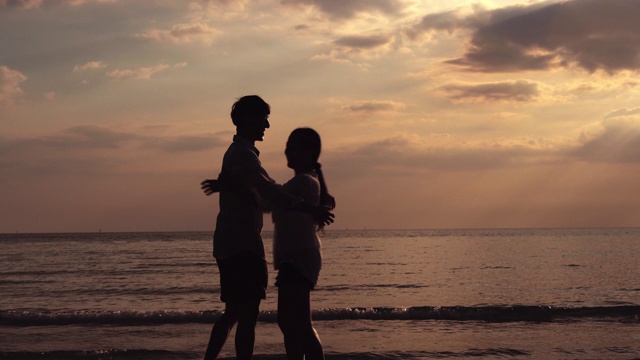 快乐的亚洲夫妇散步或跑步和牵手旋转与浪漫的海滩在夏天在一起，男人和女人约会在度假蜜月剪影，假日和旅游概念。视频素材