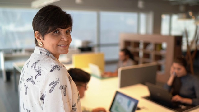 一个女商人的肖像在办公室，同事在背景视频素材