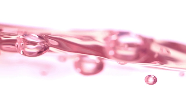 慢镜头和超微距拍摄的表面水平的粉红色沸水在选定的焦点上白色的背景视频素材