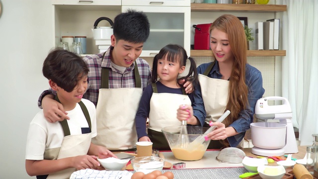 一个十几岁的女儿，儿子，父亲和母亲一起用手搅拌准备面粉。这是亚洲家庭的概念，两个孩子做饭，烘焙面包。十几岁的女孩有积极的情绪和兴奋去做这件事。视频素材