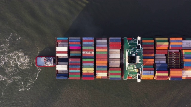航拍俯瞰一艘拖船移动一艘大型集装箱船从装载码头，Scheldt河，荷兰视频素材