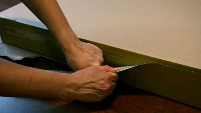 女人的手详细，从家具上拆纸箱，切割，撕扯，打开视频下载