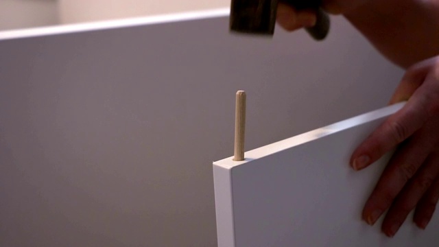 用锤子把木钉钉进家具板的人视频下载
