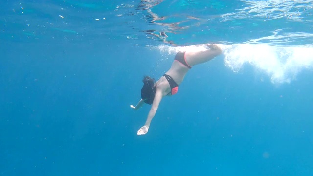 年轻女子潜入清澈的海水中。视频素材