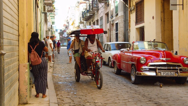 古巴哈瓦那一条狭窄的鹅卵石街道上的人力车视频下载