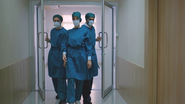 手术和外科医生团队从手术室或急诊室走出来，然后双臂交叉或站立视频素材