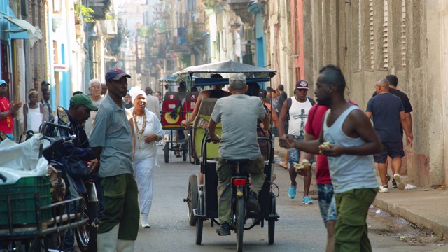 古巴哈瓦那一条繁忙的街道上，人力车在人群中穿行视频下载