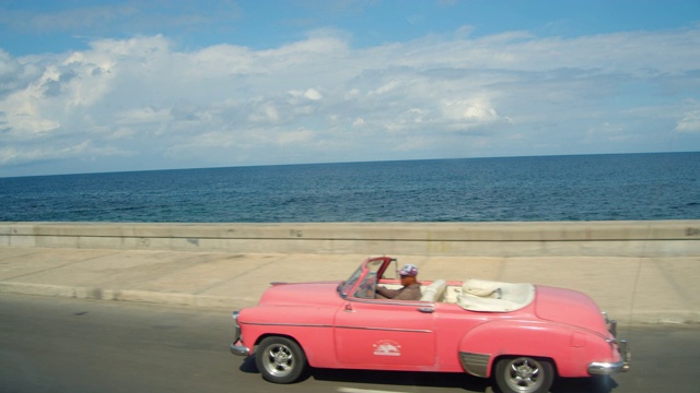 一辆粉红色的美国老爷车在哈瓦那的马雷孔路上超速行驶。古巴的标志性形象视频下载