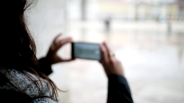 年轻女子用智能手机拍摄潮湿的欧洲城市视频素材