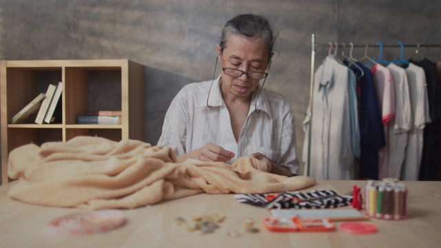 退休亚洲妇女缝纫她的衣服手工视频素材