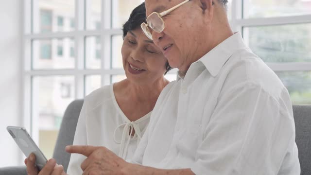 60-65岁的亚洲老年夫妇在社交距离中通过智能手机和视频会议技术通过视频会议与他们的医疗工作者交谈。高级技术的概念。视频下载