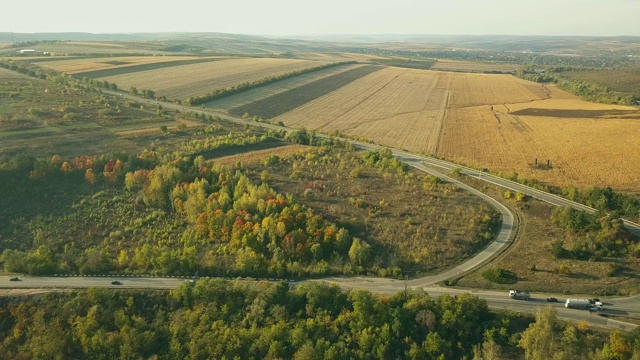 鸟瞰图飞行在令人惊叹的秋天自然和道路运行通过风景如画的乡村。路在秋景航拍。秋日的汽车驾驶道路穿过五彩缤纷的风景。视频素材