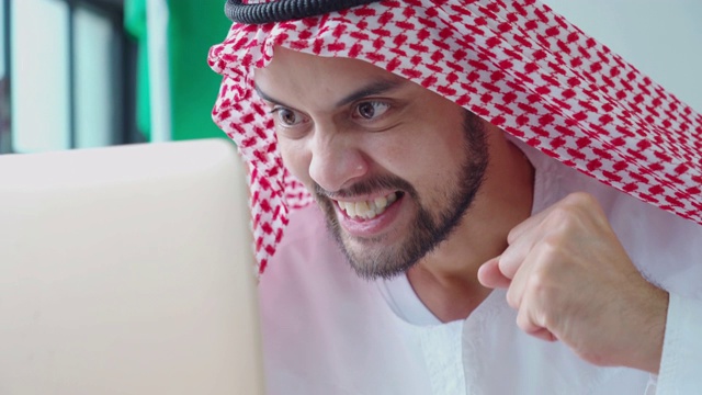 阿拉伯中东商人用笔记本电脑，兴奋和欢呼手势视频素材