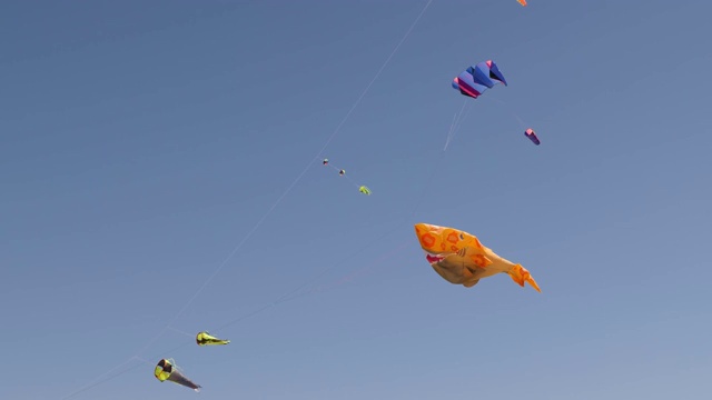 彩色的，鲨鱼形状的，旋转的风筝和蓝天的背景在慢镜头视频素材