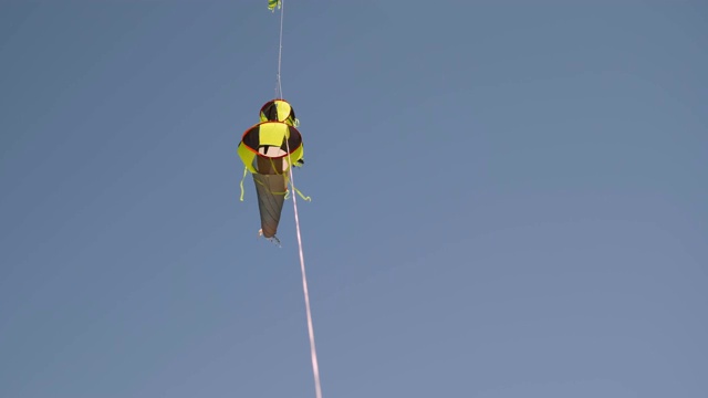 黄色和黑色的风筝挂在一根绳子上，在风中以慢动作旋转视频素材