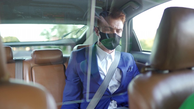 商人戴着防护面罩，进入众包出租车，检查智能手机视频素材