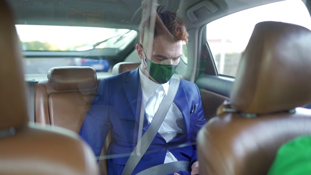 商人戴着防护面罩上网，在后座上众包出租车视频素材