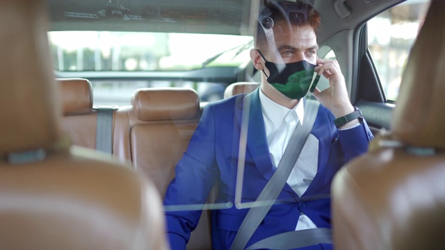 商人戴上防护面罩，坐在出租车后座上使用智能手机视频素材