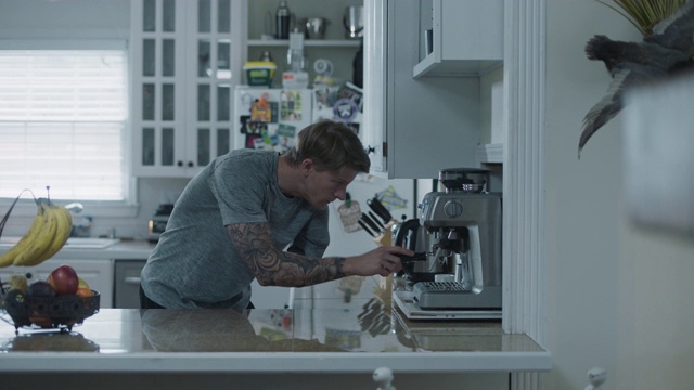 一个年轻的武装男子在厨房里准备他的早晨一杯咖啡视频素材