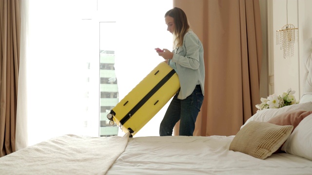 一个女人正在旅馆房间里收拾黄色的手提箱视频下载