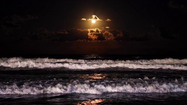 一轮满月在海浪上升起。戏剧性的日落海滩视频视频素材