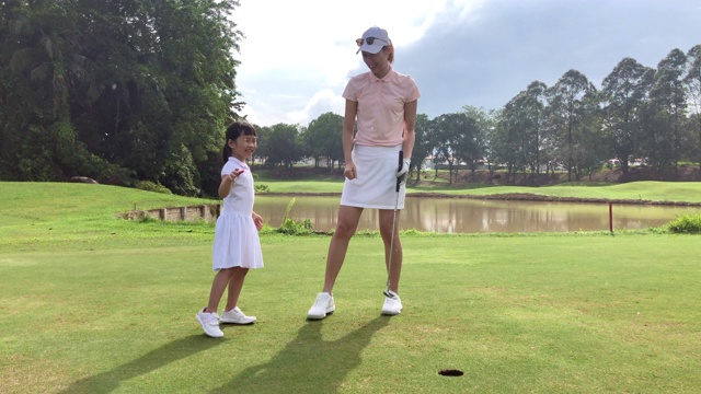 亚洲华人年轻母亲高尔夫球教她的女儿打高尔夫球场视频下载