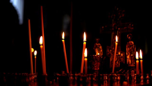 金色的东正教卡努与燃烧的蜡烛在黑暗的房间的背景视频素材