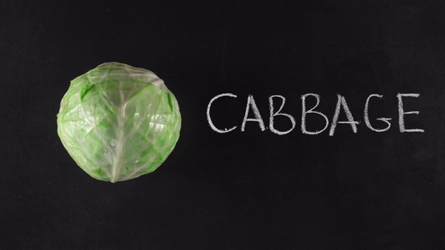 定格动画与绿色卷心菜和手写文字在黑色黑板上，俯视图。素食的概念或蔬菜广告视频下载