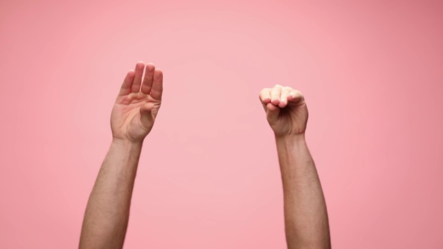 在粉红色的背景上，一个男人在空中举着手臂，聊天，打手势视频素材