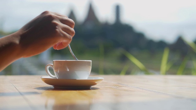 一个女人用咖啡勺的手，背景是泰国一个美丽的旅游目的地。视频素材