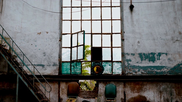 一座废弃的旧建筑的破碎玻璃窗户随着风的开关和关闭视频下载