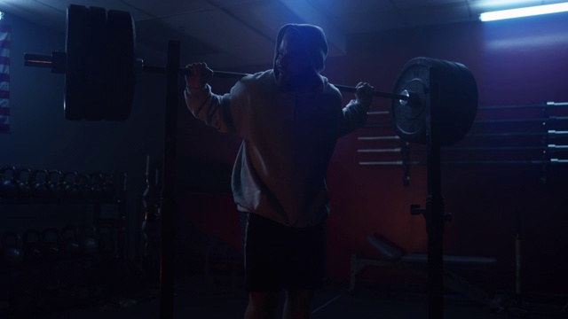 新冠肺炎大流行期间，帅气肌肉运动员在健身房用杠铃做下蹲视频下载
