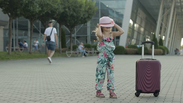 带着行李箱的女游客在机场附近。小朋友们跳舞，跳跃，带着行李庆祝视频素材