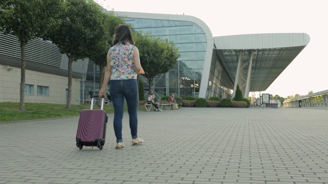 带着行李去机场的女商人。女孩边走边拉手提箱。旅游视频素材