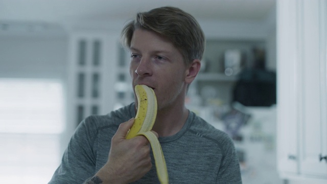 一只年轻的手臂剥开香蕉，咬了一口视频素材