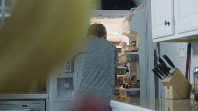 一个持枪的运动员从冰箱里拿出一盒牛奶，倒进一个碗里视频素材