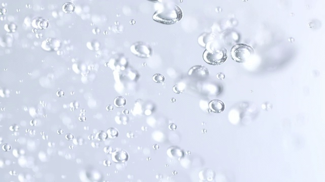 慢镜头和超微距镜头的倒水，使微小的气泡在水下轻银色的背景视频下载