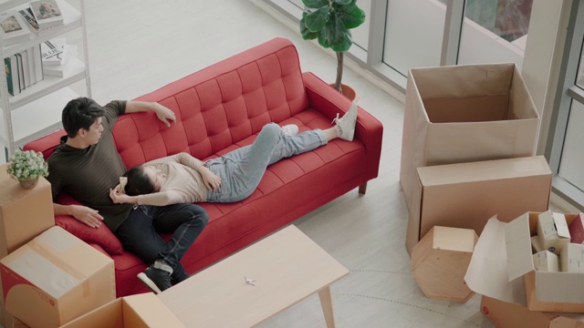 快乐的年轻亚洲夫妇把新沙发搬到客厅视频素材