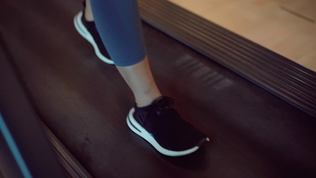 一个亚洲女孩开始戴着耳机在健身房里的跑步机上跑步视频素材