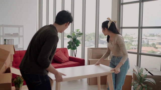 快乐的年轻亚洲夫妇把新沙发搬到客厅视频素材