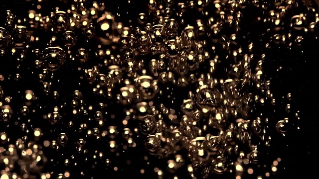 慢镜头和超微距镜头的倒水，使金色的小气泡水下在一个黑色的背景视频素材