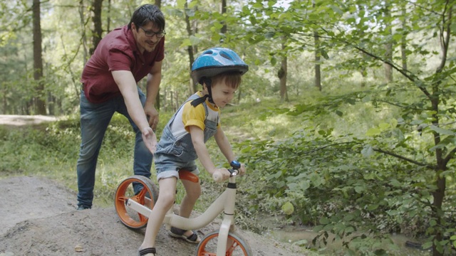 一个男人在教他的孩子骑自行车视频素材