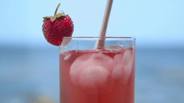 在海边的草莓鸡尾酒中加入冰块，混合使其更冷视频下载