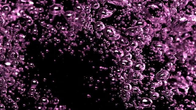 慢动作和超微距镜头的倒水使粉红色的小气泡水下在一个黑色的背景视频素材