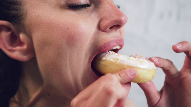 女人在吃甜甜圈，特写。视频素材