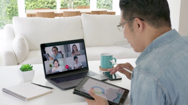 缩小后视:商人在视频会议中交谈。亚洲团队使用笔记本电脑和平板电脑进行在线视频会议。在家工作，远程工作和在家自我隔离视频下载