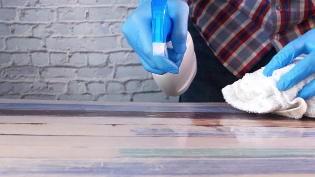 手持喷瓶和清洁桌子的蓝色橡胶手套视频素材