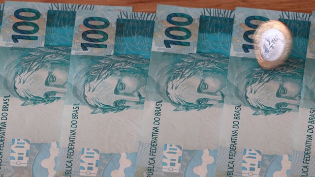 巴西1雷亚尔硬币旋转上大量的100真钞票视频素材
