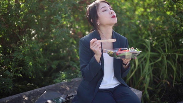 年轻女商人吃沙拉，在公园吃午餐视频下载