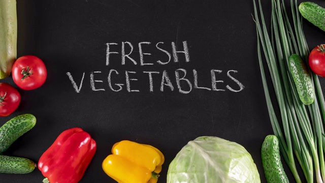 定格动画与许多彩色蔬菜和手写文字在黑色黑板上，俯视图。素食或广告的概念视频下载